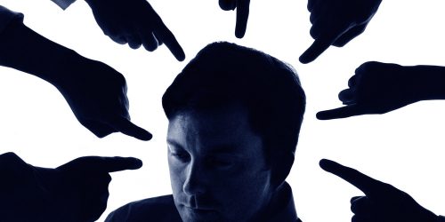 People pointing at businessman, close-up (blue tone, grainy)